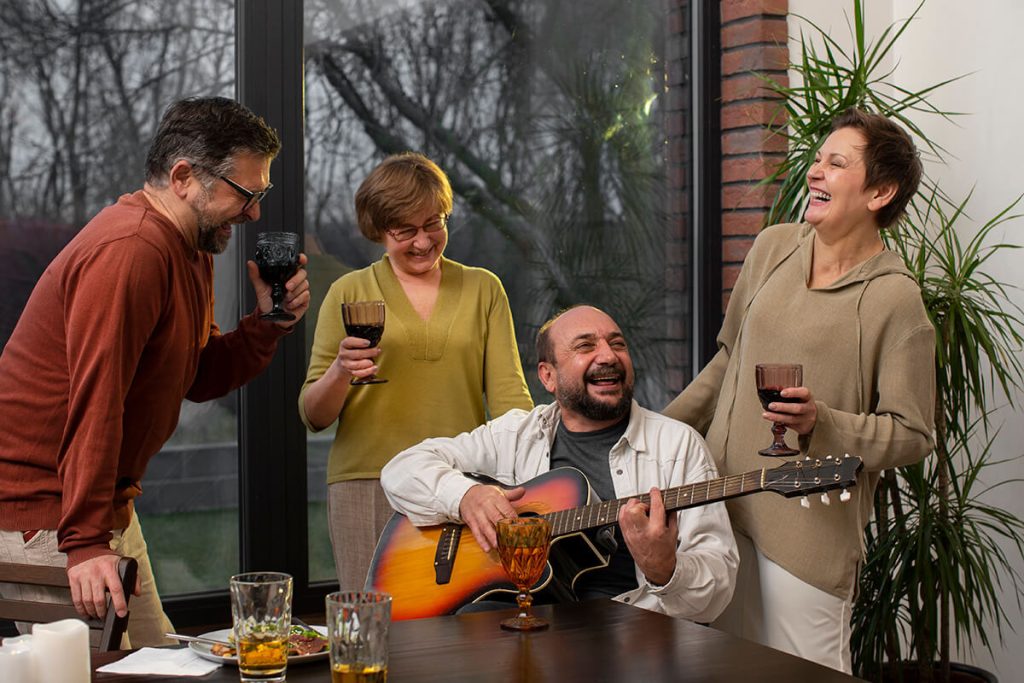 Group of adults enjoying music, laughter, and connection around a dinner table, highlighting sober night life