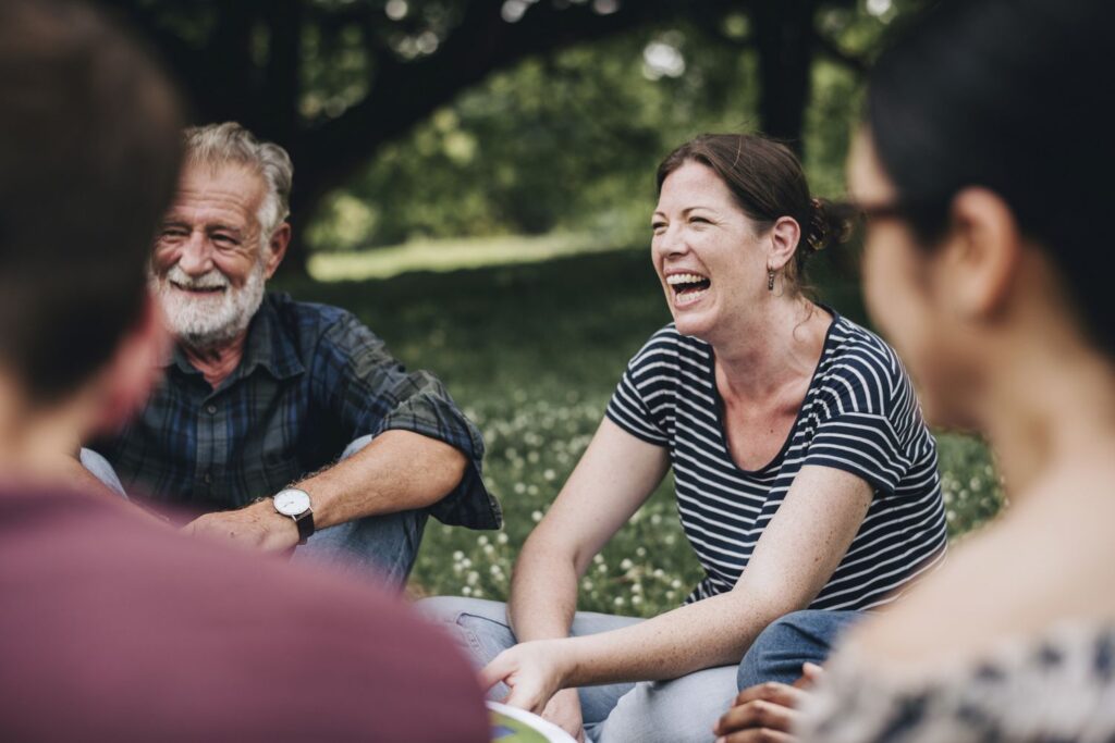 Group of people smiling and connecting outdoors during adventure therapy at Capo Beach Recovery in San Juan Capistrano, California, promoting healing and teamwork in substance use disorder treatment.